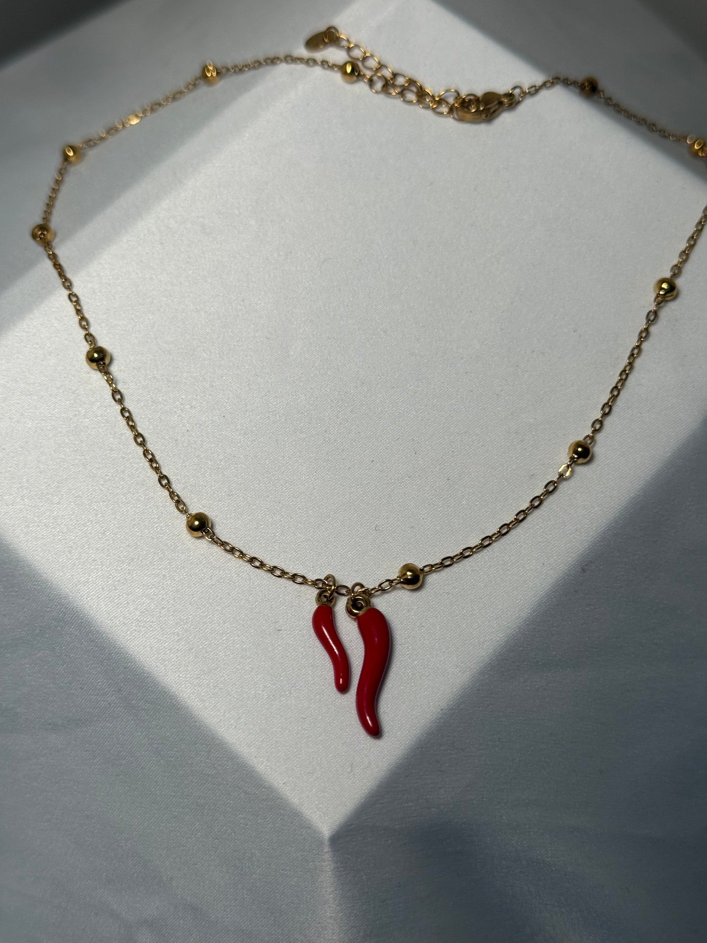 Double red horns on gold colored ball necklace