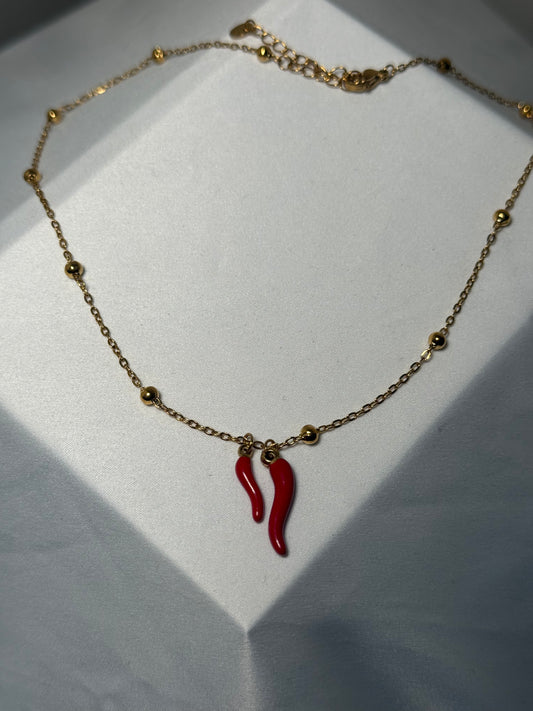 Double red horns on gold colored ball necklace