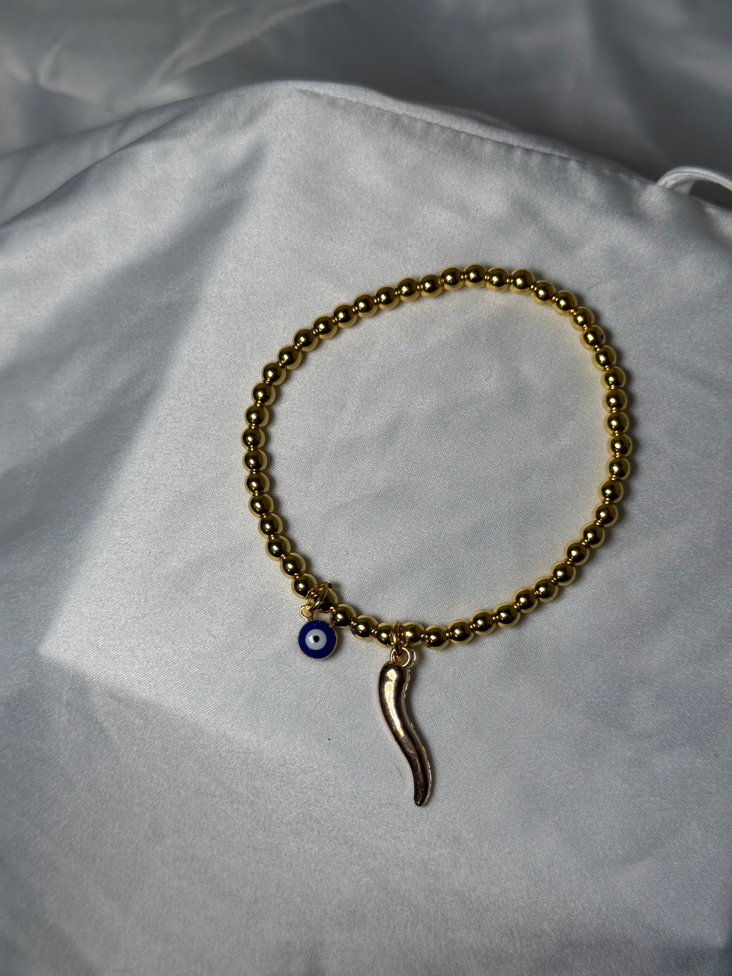 Gold beaded evil eye, and horn bracelet