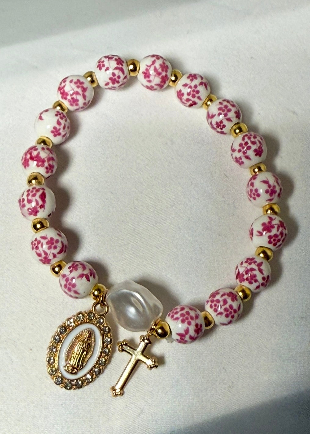 Pink and white ceramic beaded bracelet with gold colored blessed mother and cross