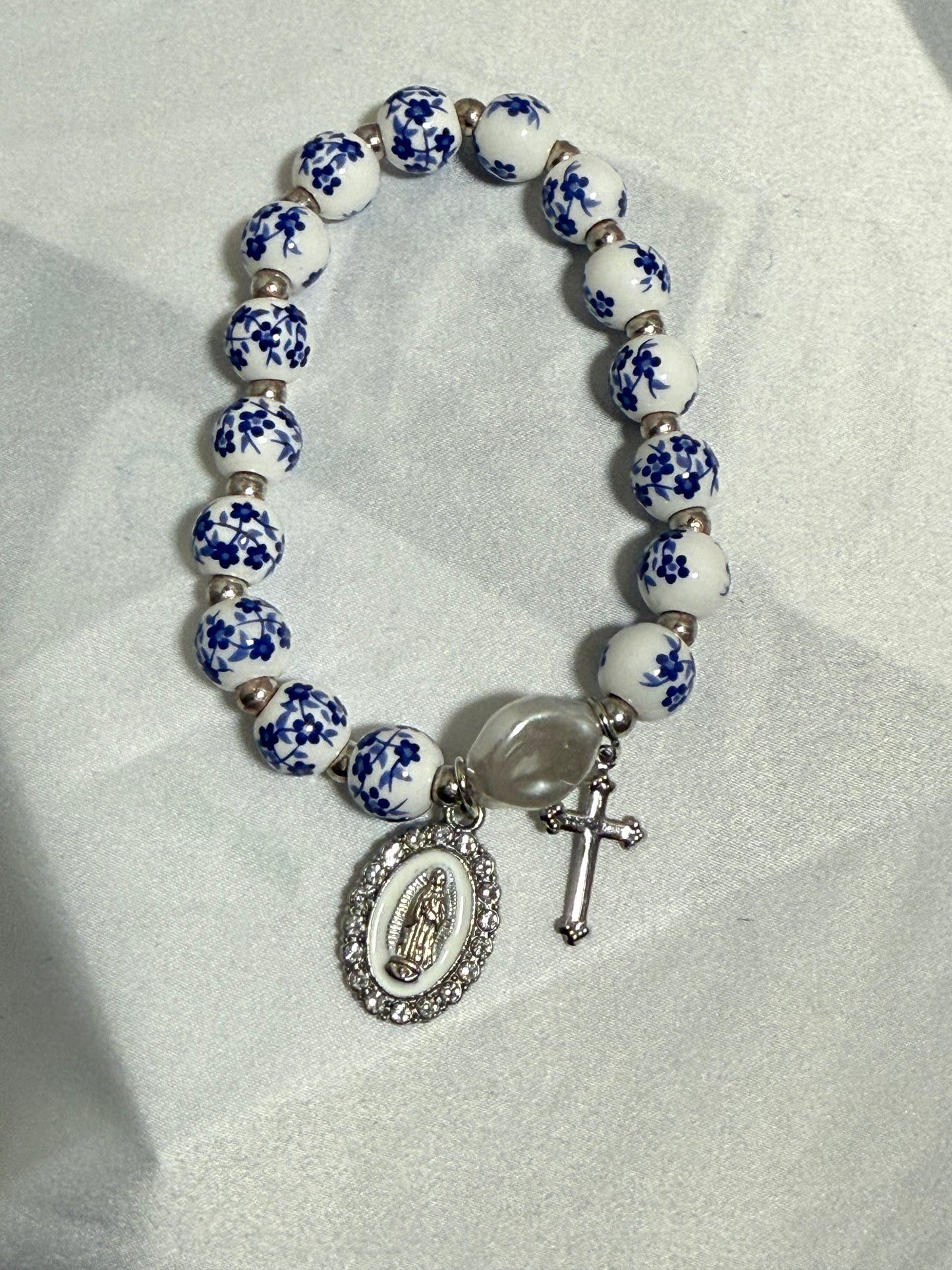Blue and white beaded bracelet with the blessed mother and cross in silver color