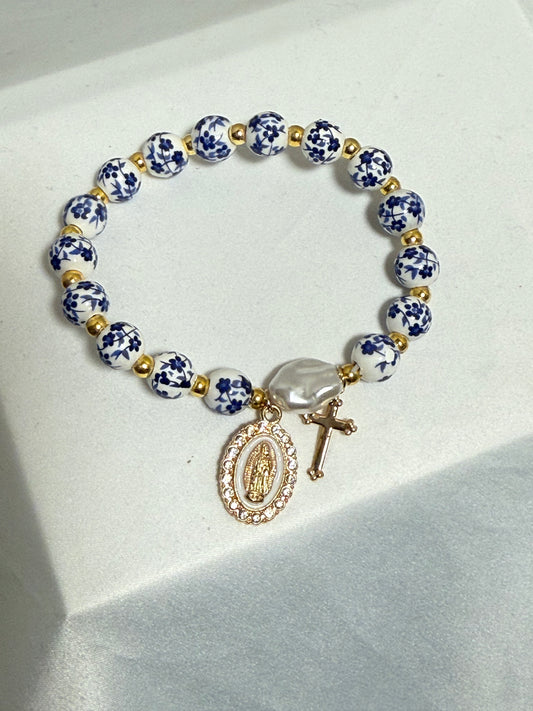 Blue and white beaded bracelet with blessed mother and cross in gold color